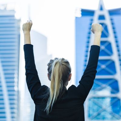 Business,Success,-,Celebrating,Businesswoman,Overlooking,The,City,Center,High-rises.